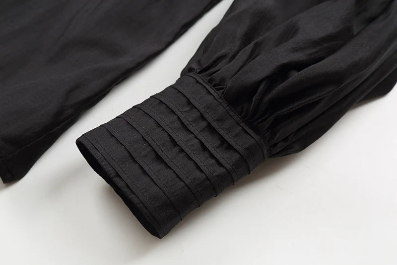 Close-up of a black sleeve with pleated cuffs on a white background