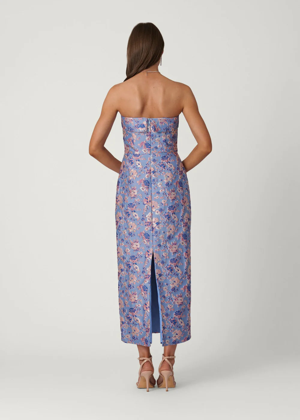 Woman wearing a strapless floral dress with a slit on a white background