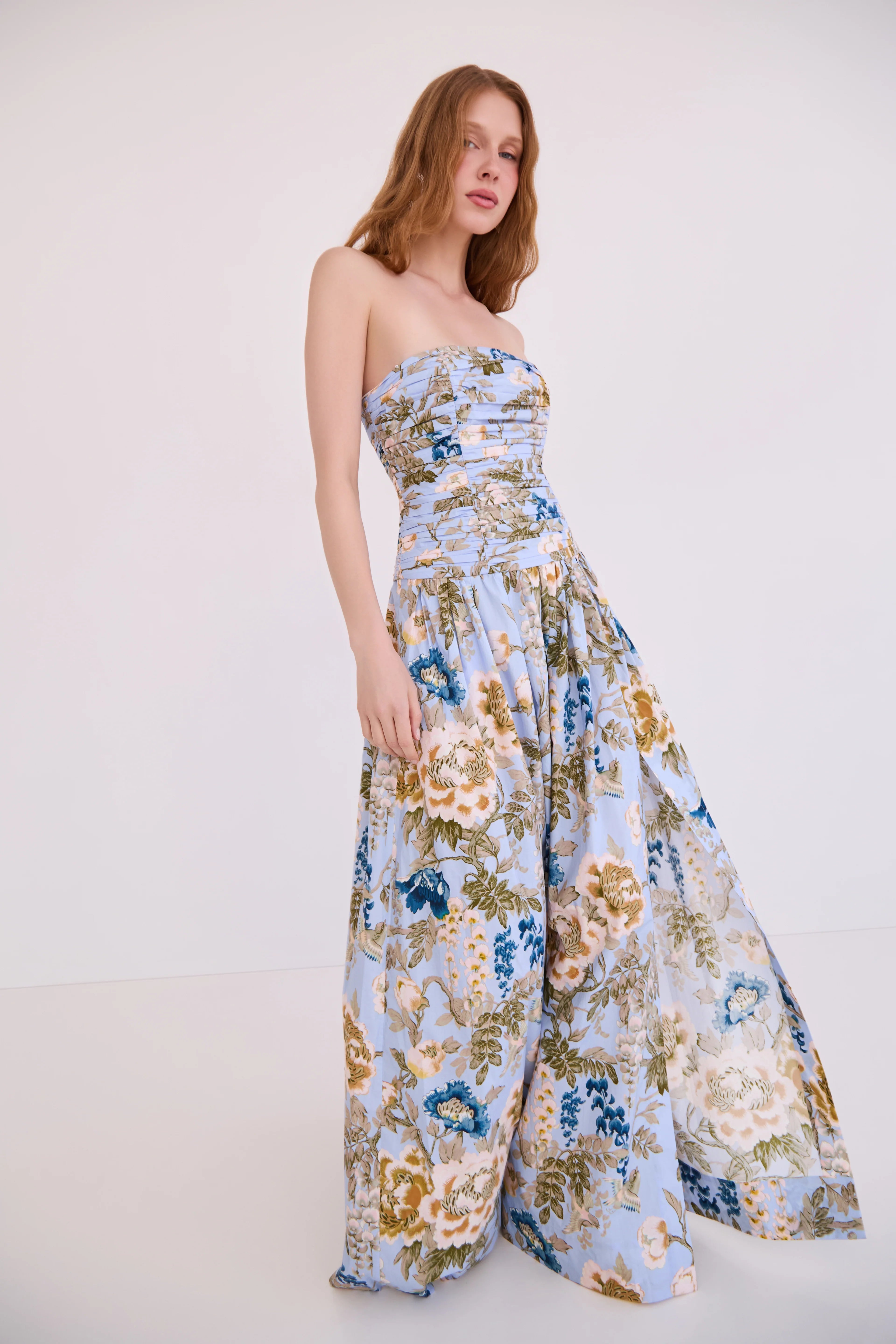 Woman wearing a strapless floral jumpsuit on a white background