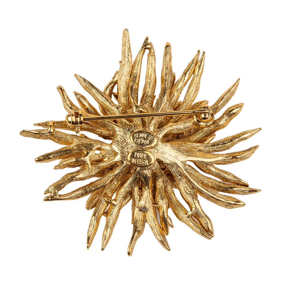 Gold sunburst brooch with 'Chantecler' branding on a white background