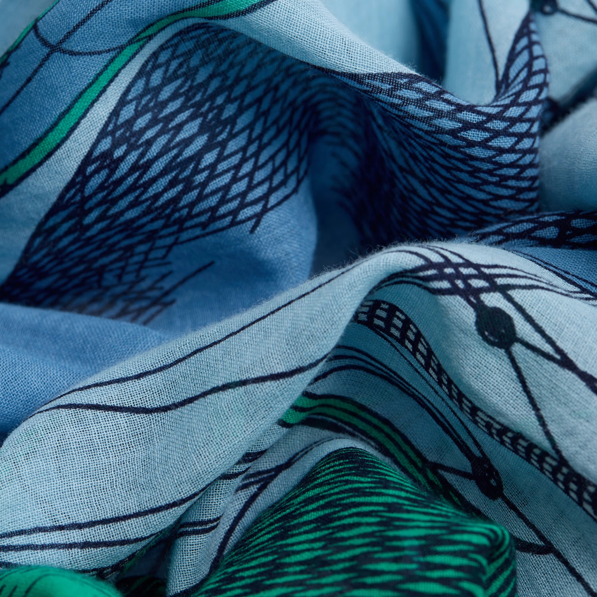 Close-up of blue fabric with black and green abstract patterns