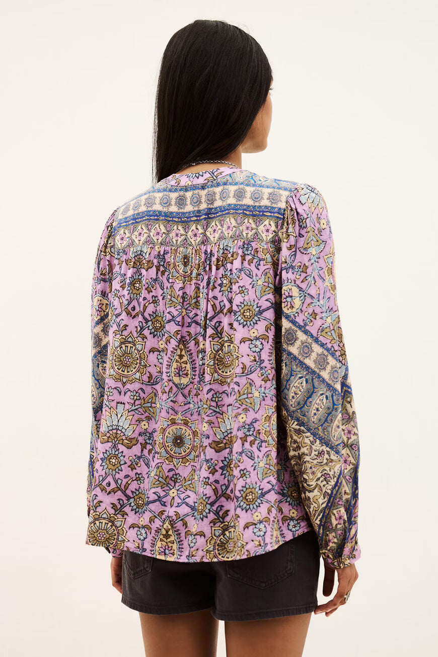 Person wearing a patterned blouse with a white background