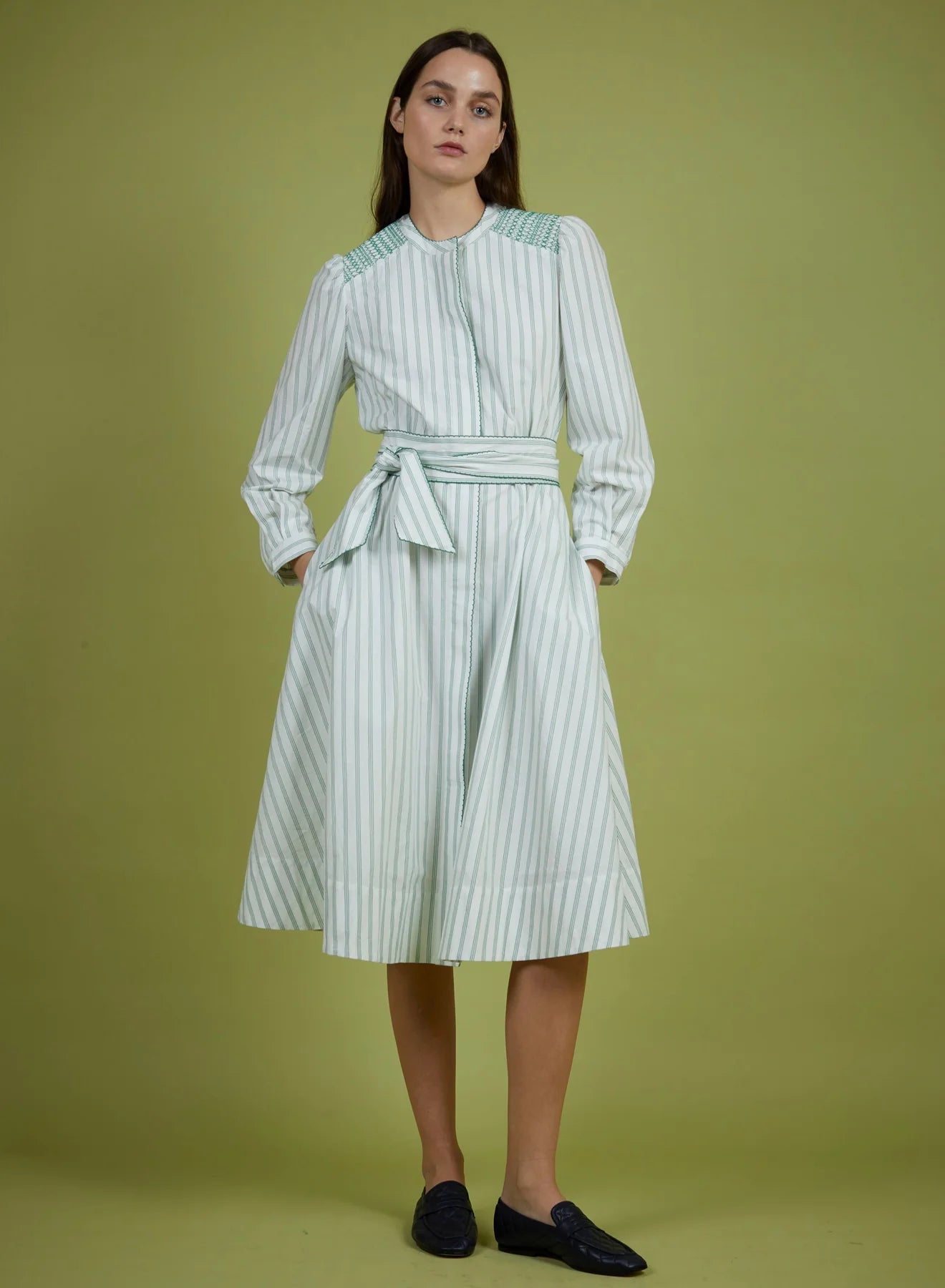 Woman wearing a green and white striped dress against a green background