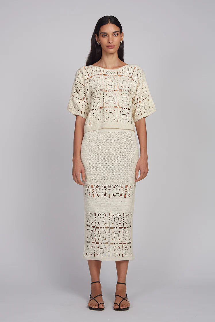 Woman wearing a cream-colored lace outfit on a plain background