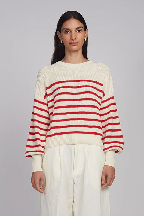 Woman wearing a red and white striped sweater against a plain background