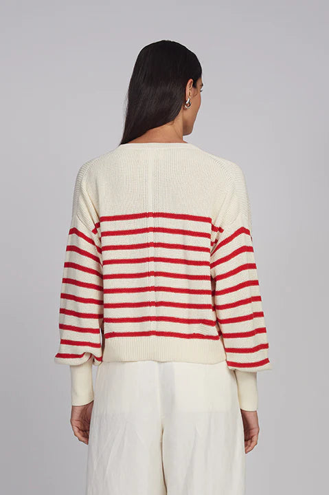 Person wearing a cream and red striped sweater on a gray background