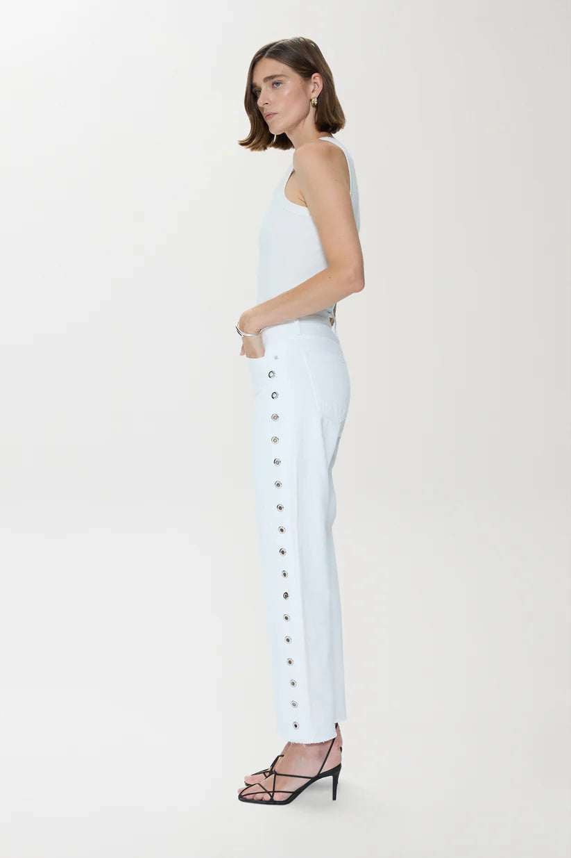 Woman wearing a white tank top and pants with buttons on a white background