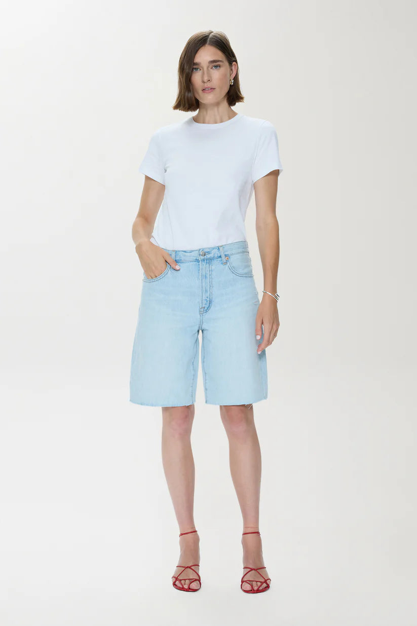 Woman wearing a light blue t-shirt and denim shorts on a white background