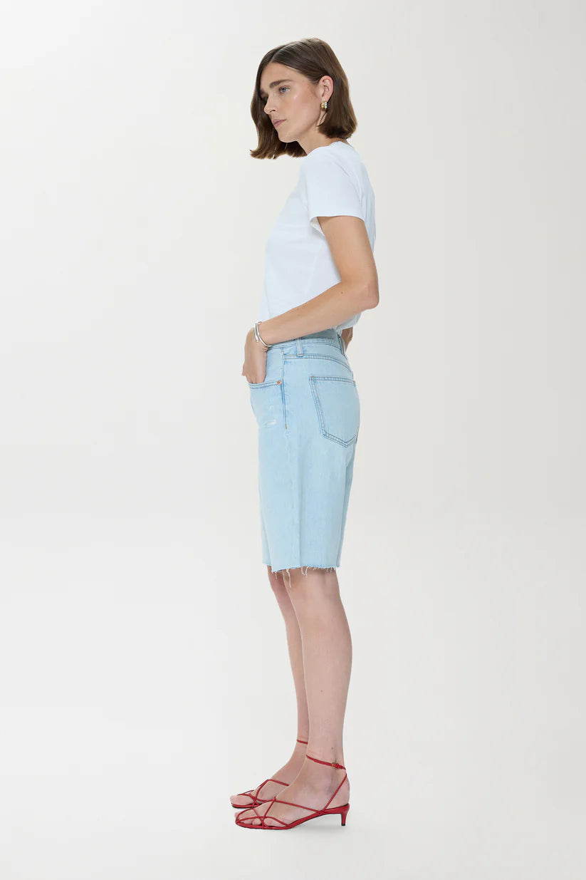 Woman wearing a light blue t-shirt and denim shorts on a white background