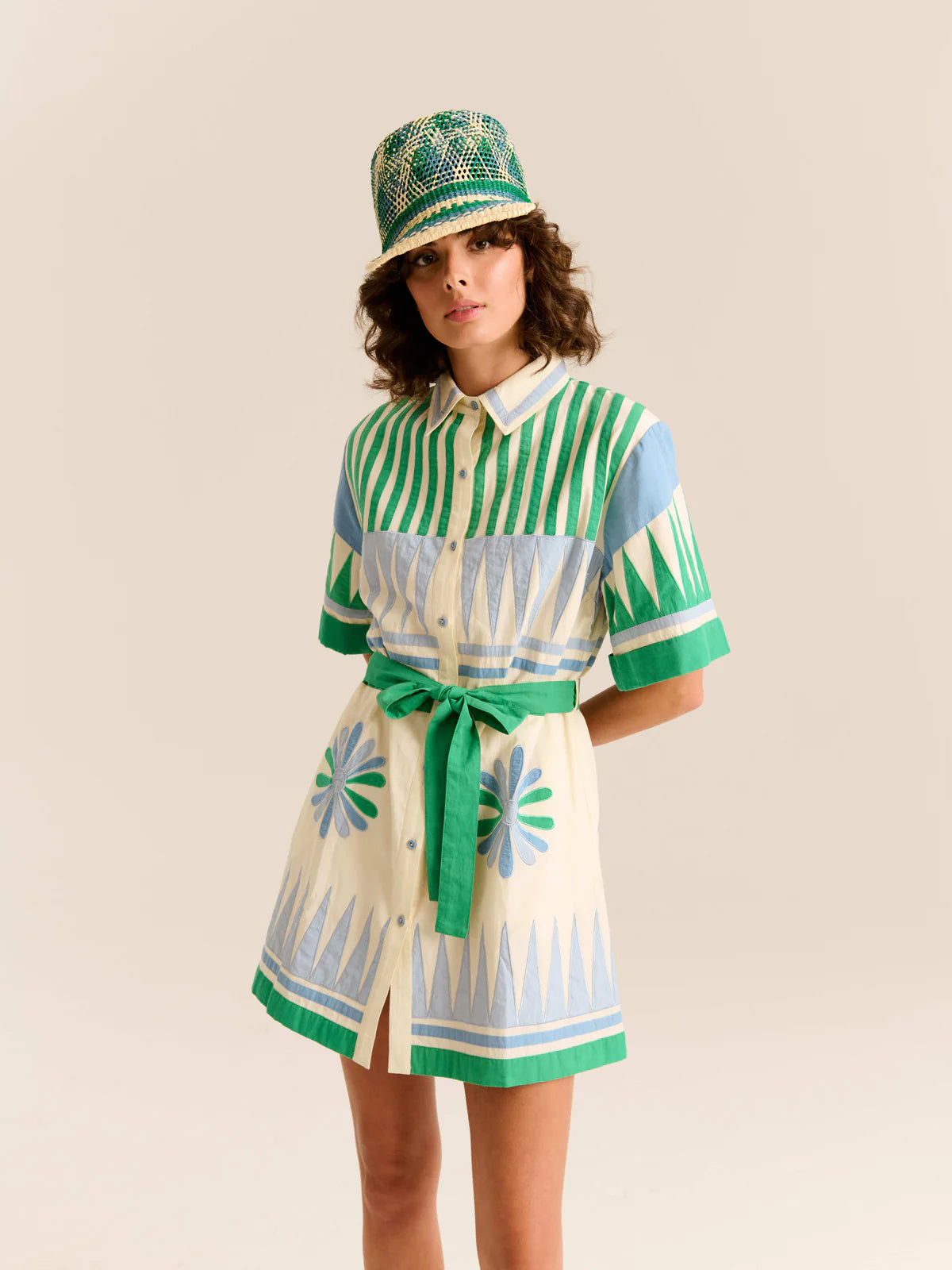 Person wearing a green and white striped outfit with a matching hat on a beige background