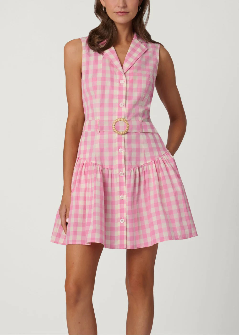 Woman wearing a pink checkered dress with a belt on a white background