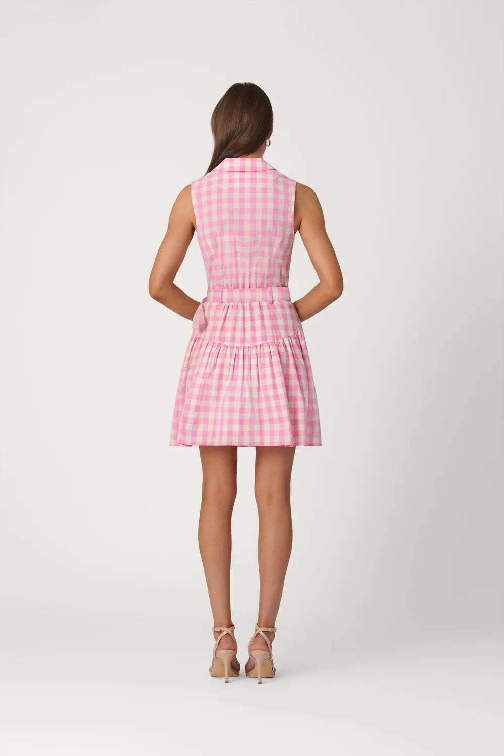Woman wearing a pink checkered dress on a white background