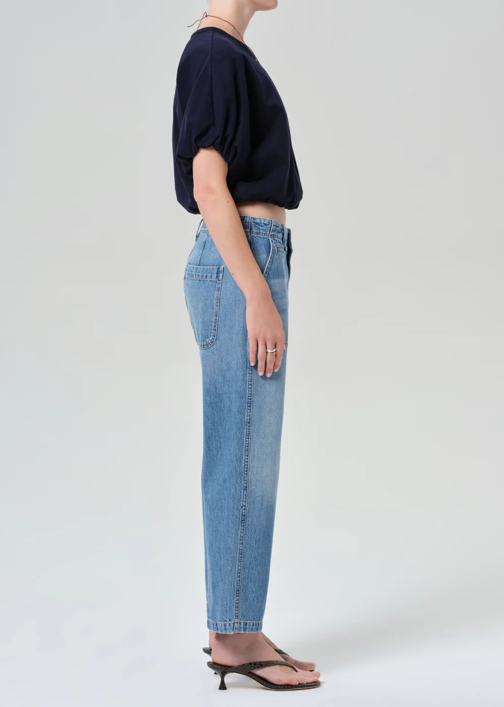 Person wearing a navy sweater and light blue jeans on a white background