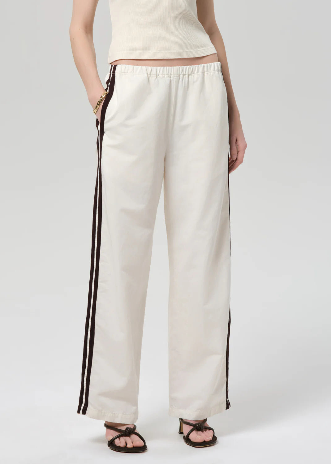 White pants with black stripes worn by a person on a white background