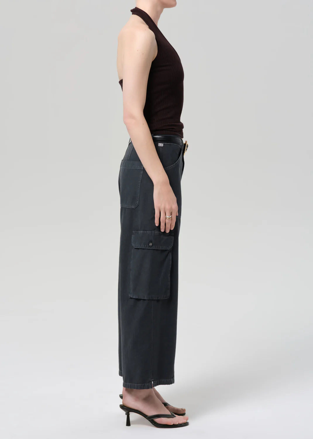 Person wearing black sleeveless top and cargo pants on a white background