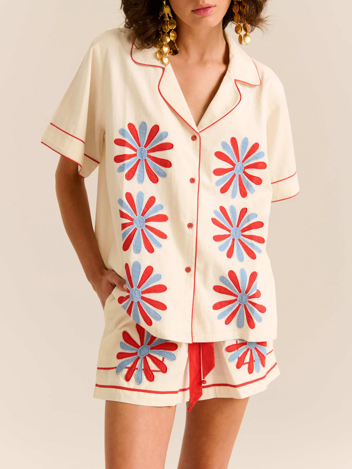 Woman wearing a cream-colored pajama set with red and blue floral patterns on a plain background