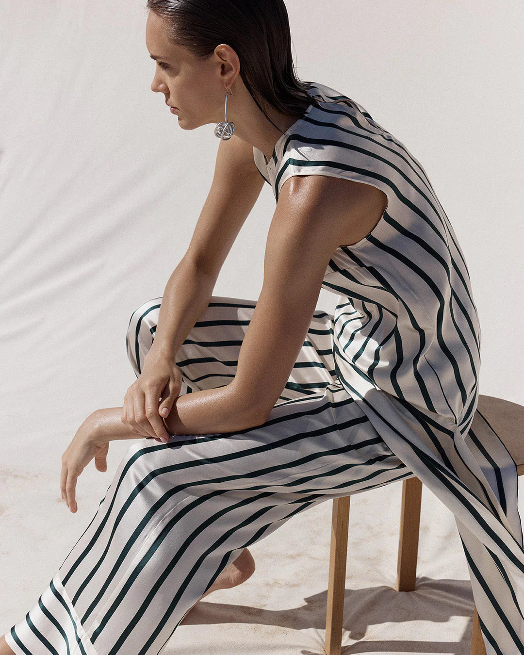 Woman sitting on a chair wearing a black and white striped outfit.
