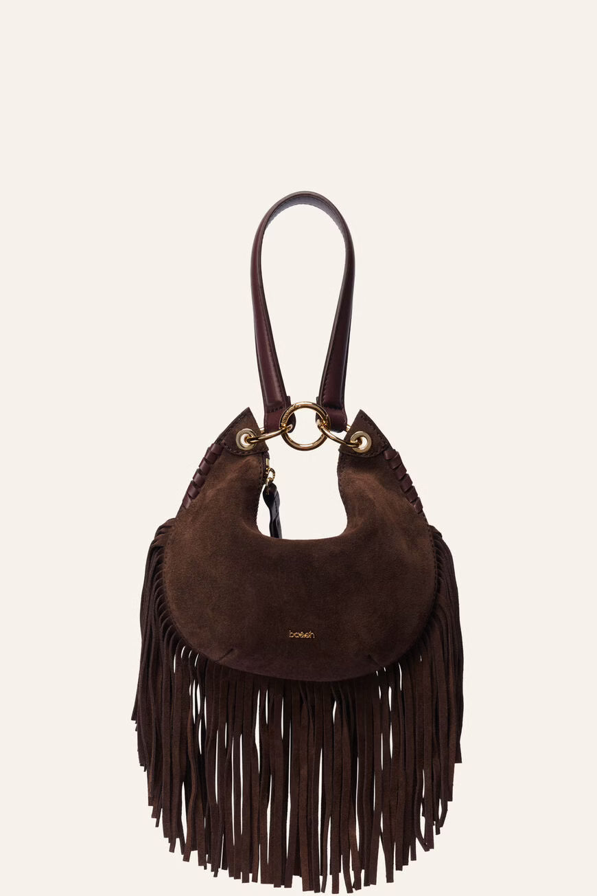 A dark brown suede crescent-shaped shoulder bag with a long fringe tassel, a matching top handle, and gold-tone hardware, shown against a solid off-white background.