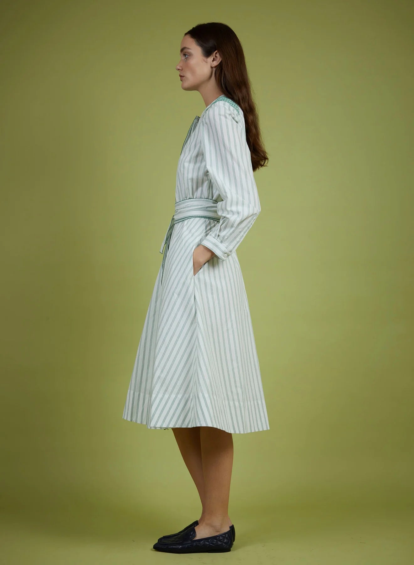 Woman wearing a striped dress against a green background