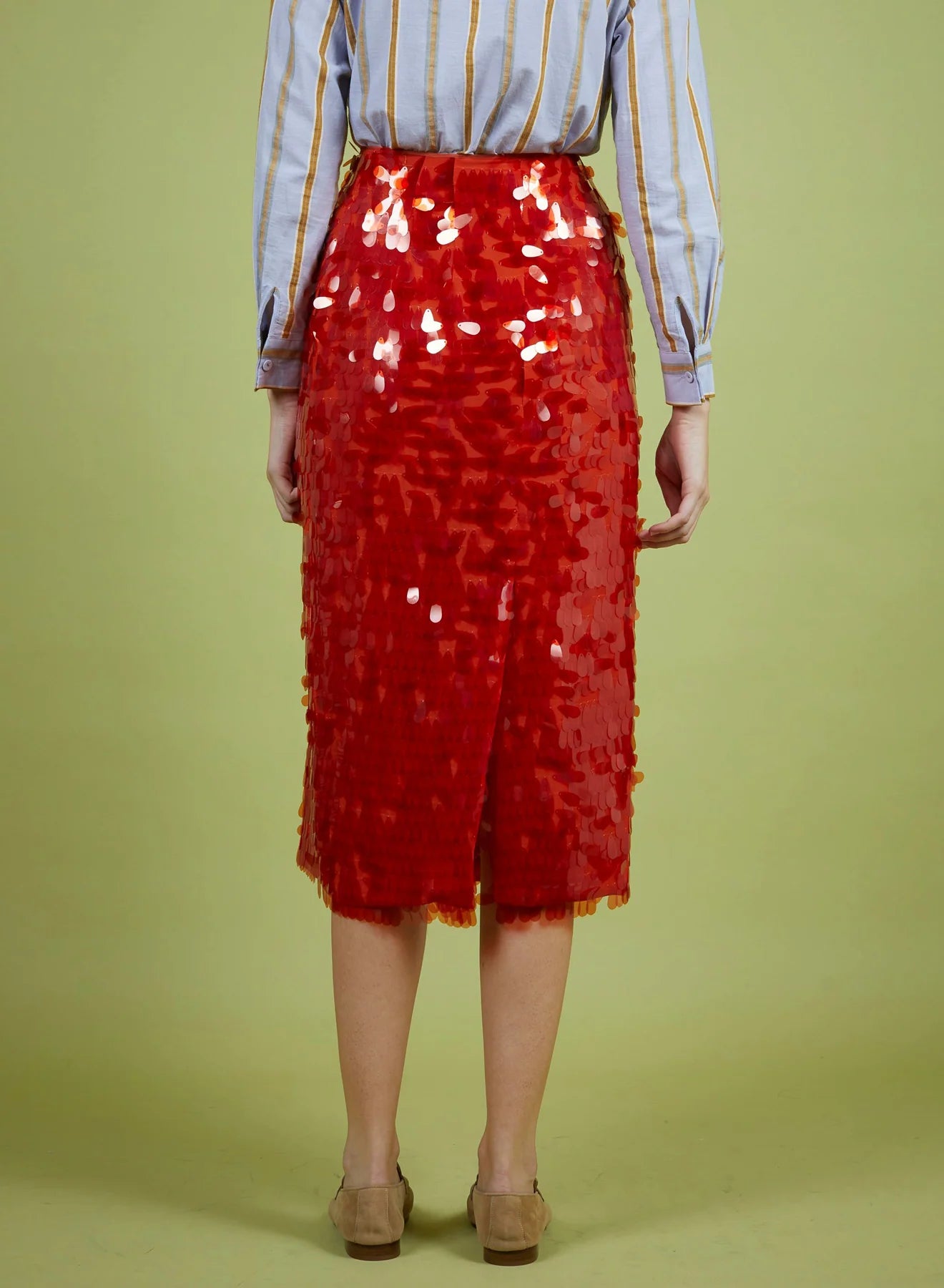 Person wearing a red sequin skirt on a green background