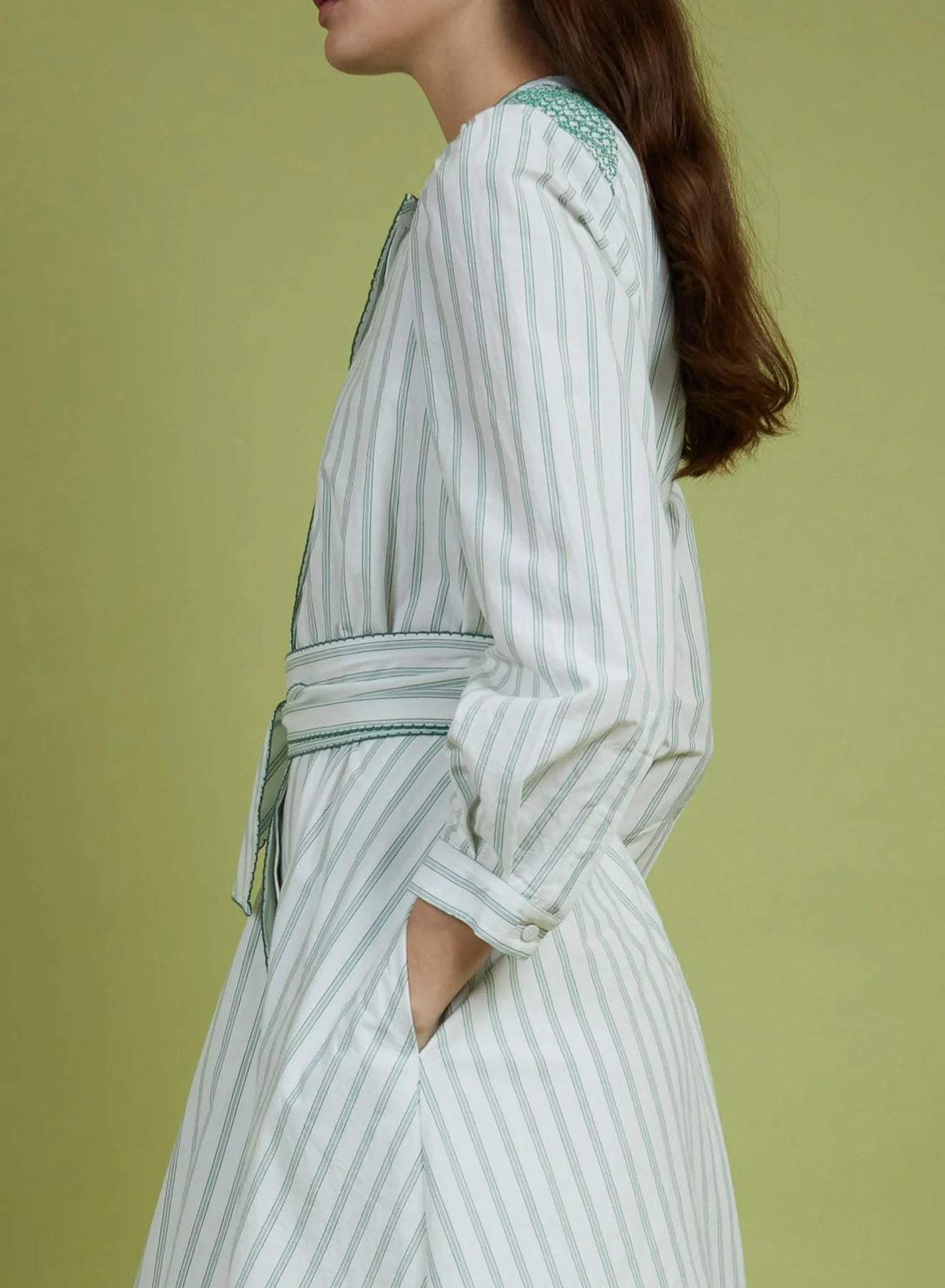 Woman wearing a white and green striped dress against a solid background