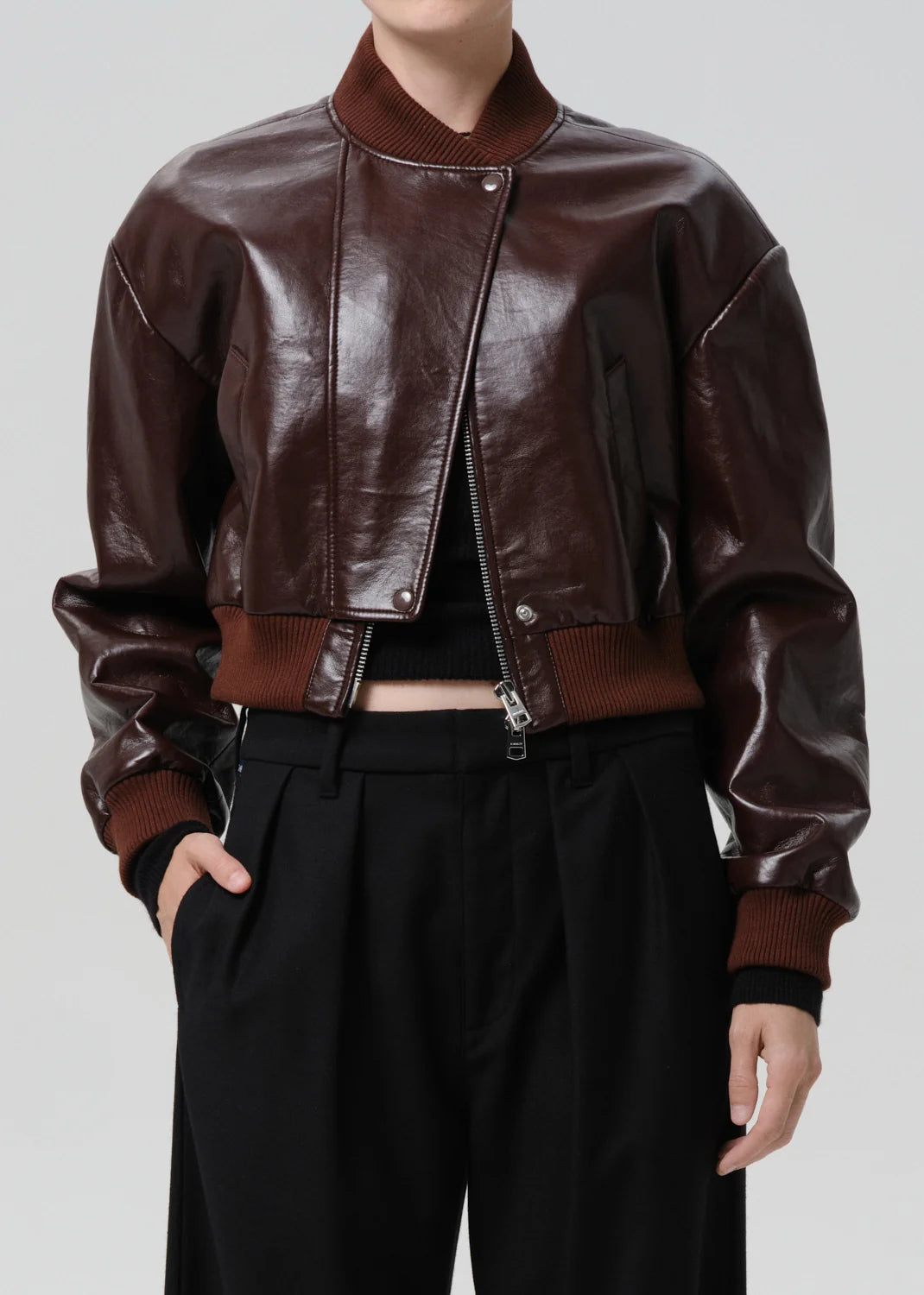 Brown leather jacket worn by a person on a plain background