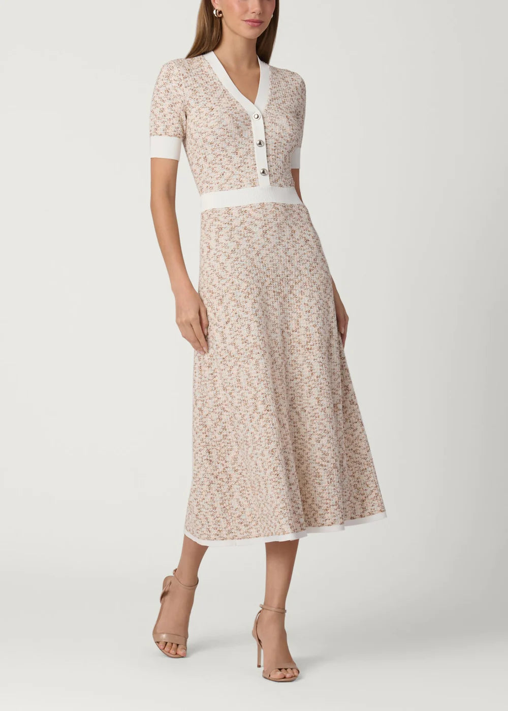 Woman wearing a patterned dress with a white belt on a plain background