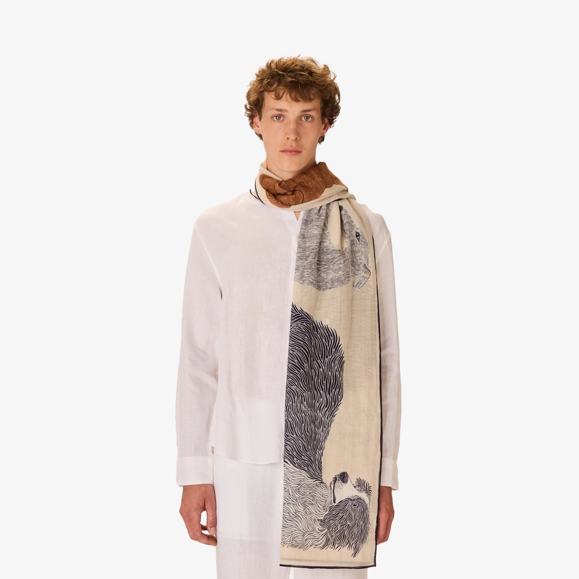 Person wearing a long, patterned scarf with a neutral background