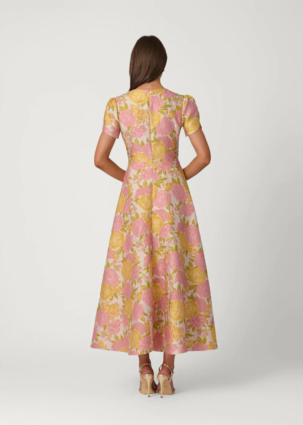 Woman wearing a pink and yellow floral dress on a white background
