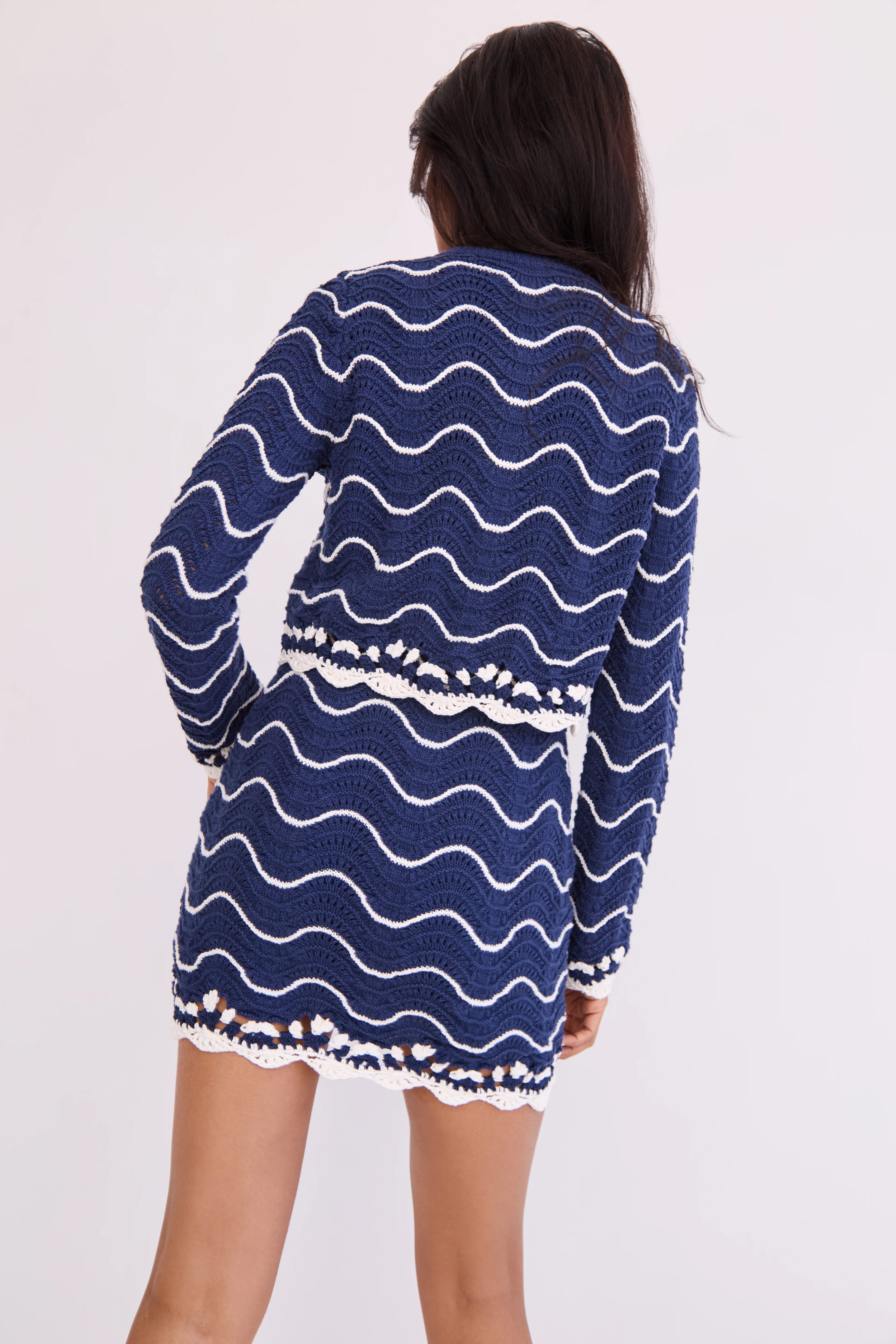 Woman wearing a blue dress with white wave patterns on a plain background