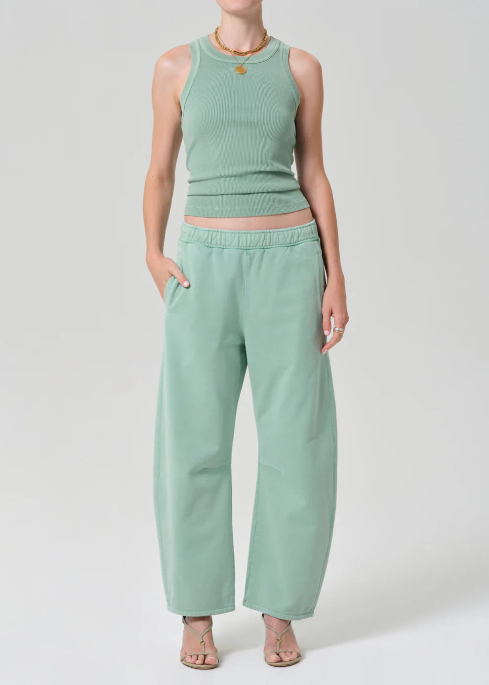 Person wearing a mint green sleeveless top and pants on a white background
