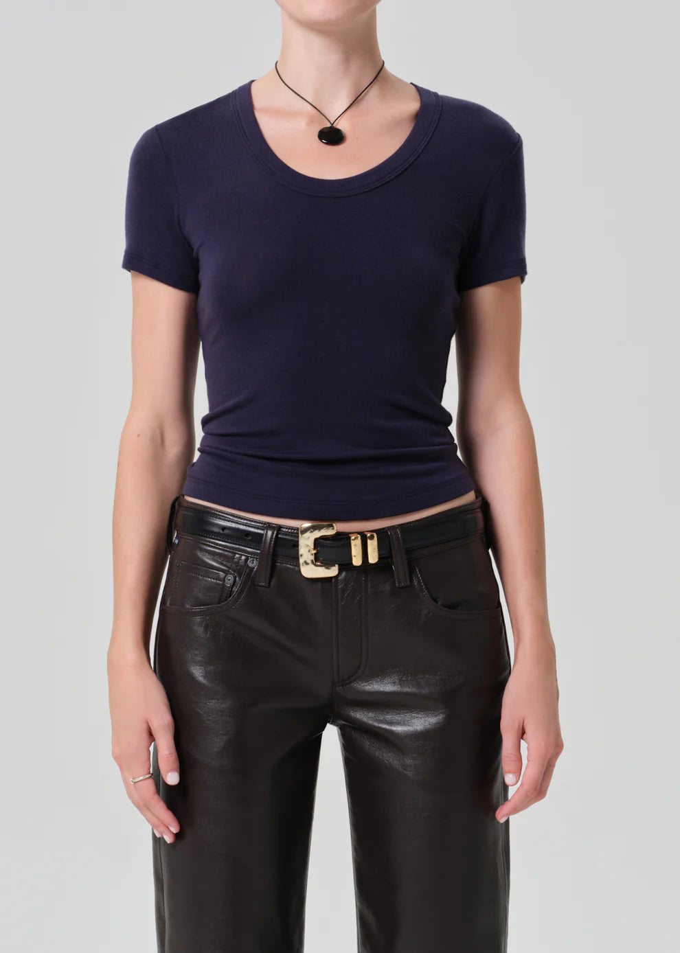 Person wearing a navy blue top and black leather pants on a gray background