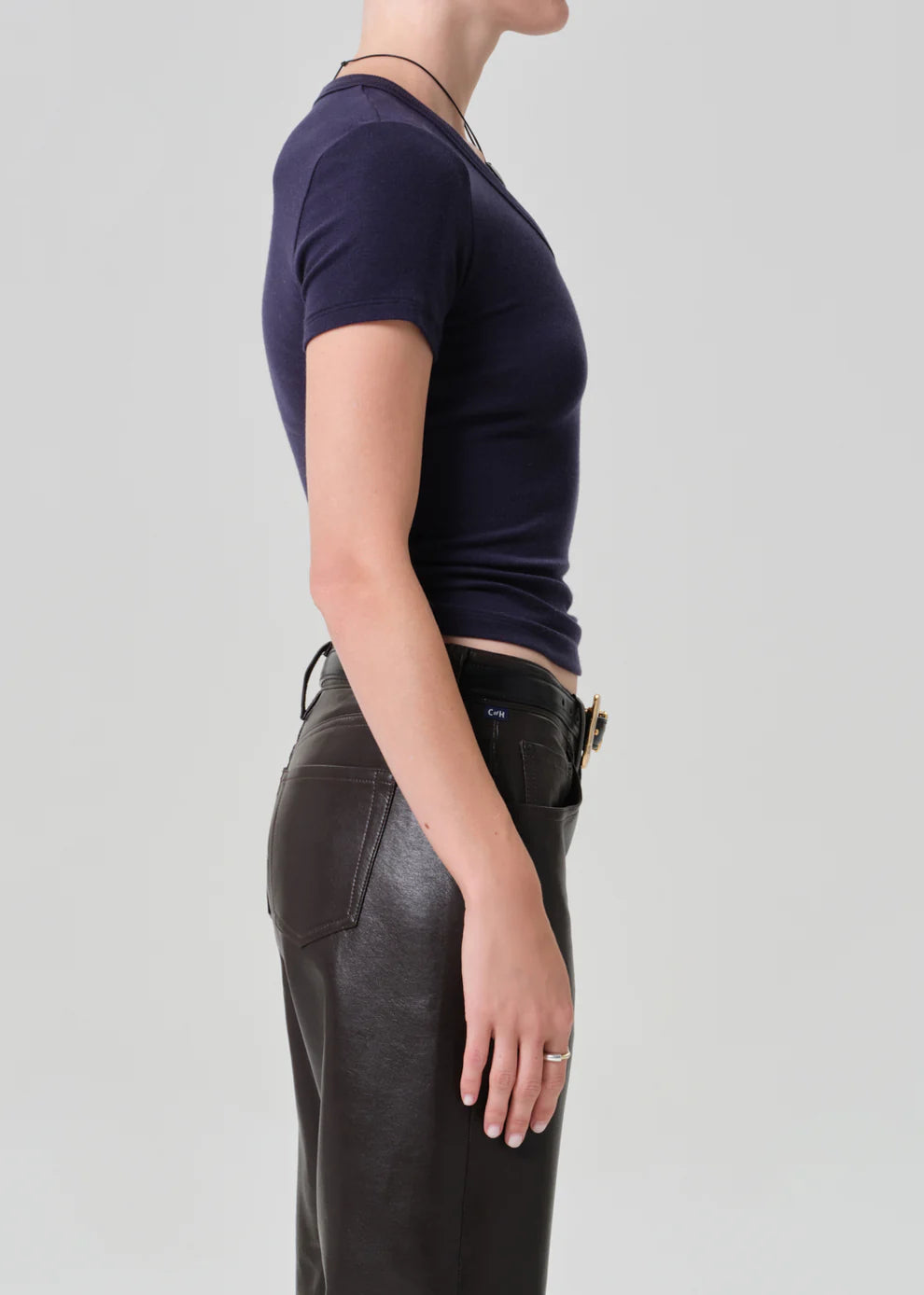 Person wearing a dark blue t-shirt and black leather pants on a light gray background
