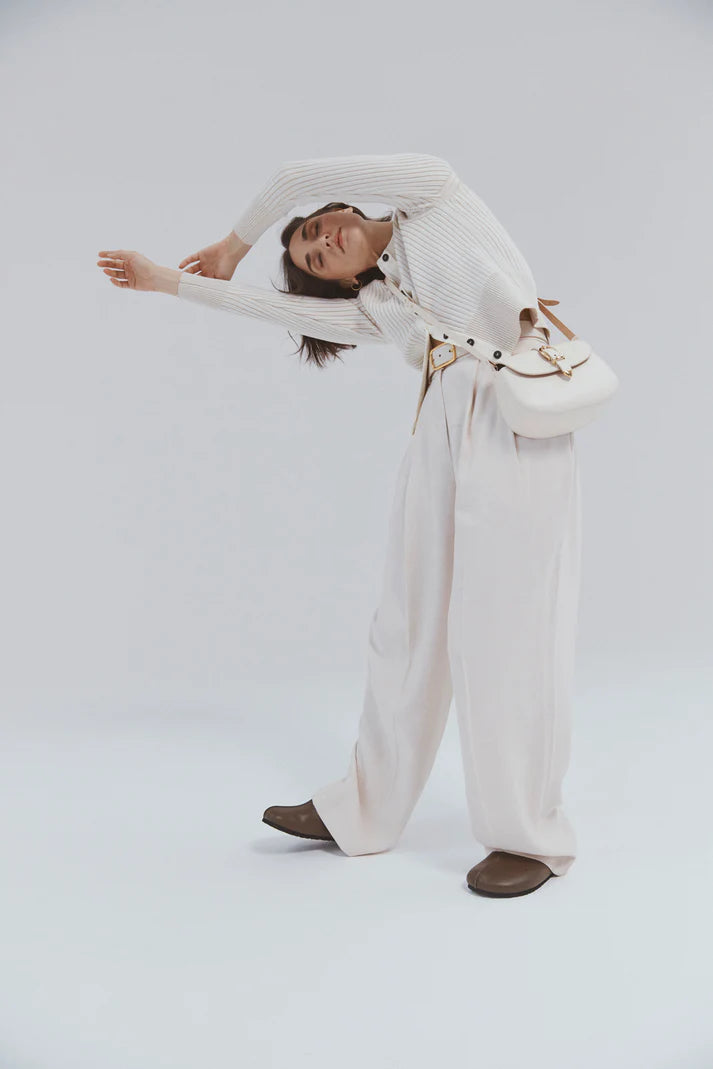 Woman in a white outfit with a white bag on a light gray background
