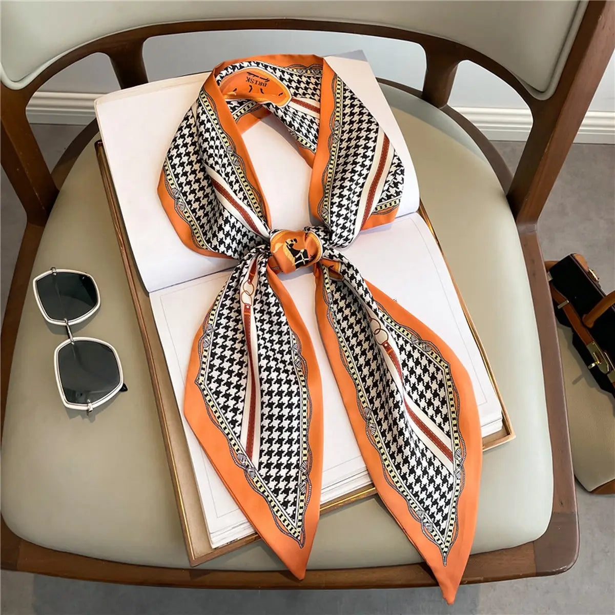 Houndstooth patterned scarf with orange border on a chair