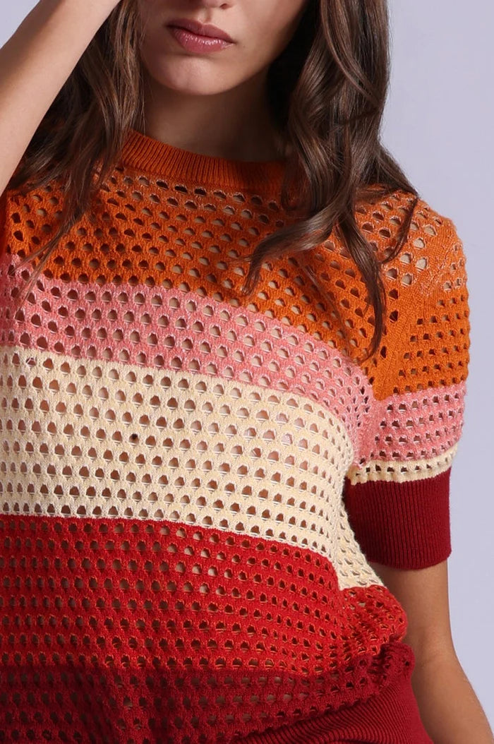 Colorful crochet sweater worn by a person on a plain background