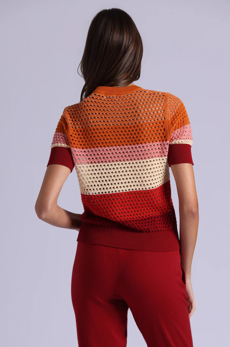 Woman wearing a colorful knit top with a plain background