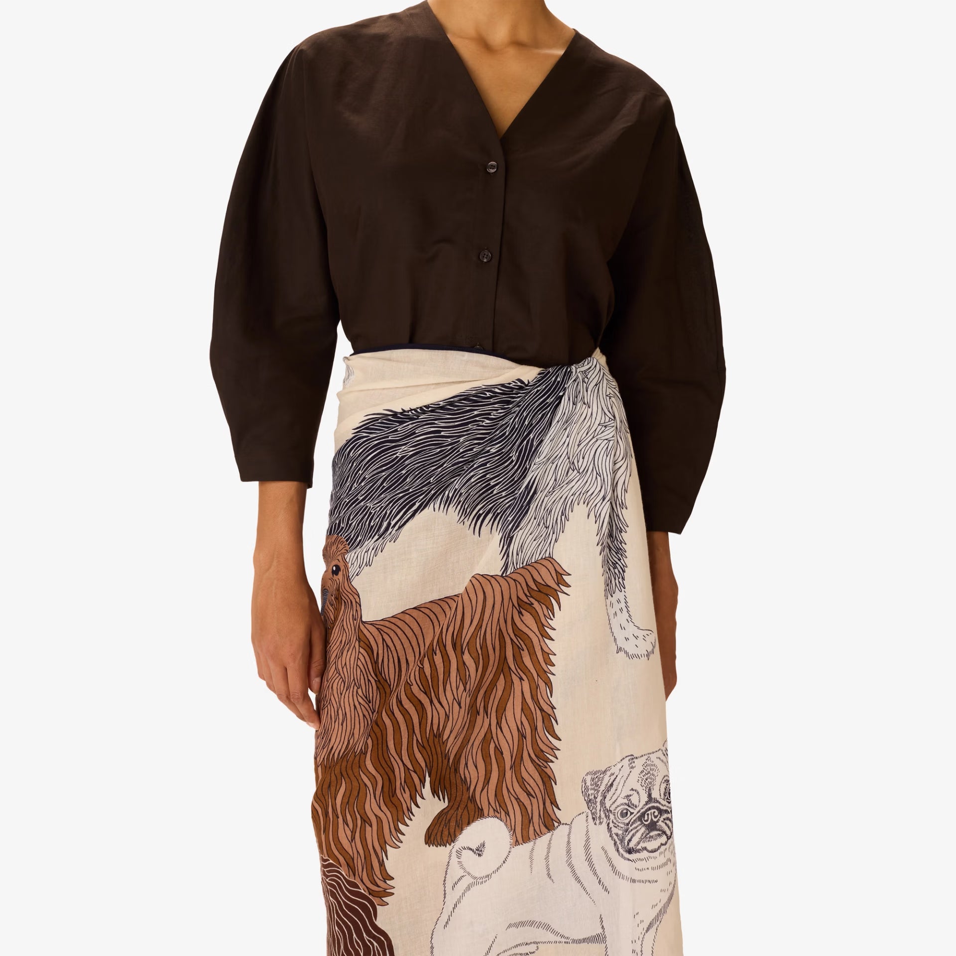 Person wearing a brown blouse with a long, patterned skirt featuring animal illustrations on a white background.