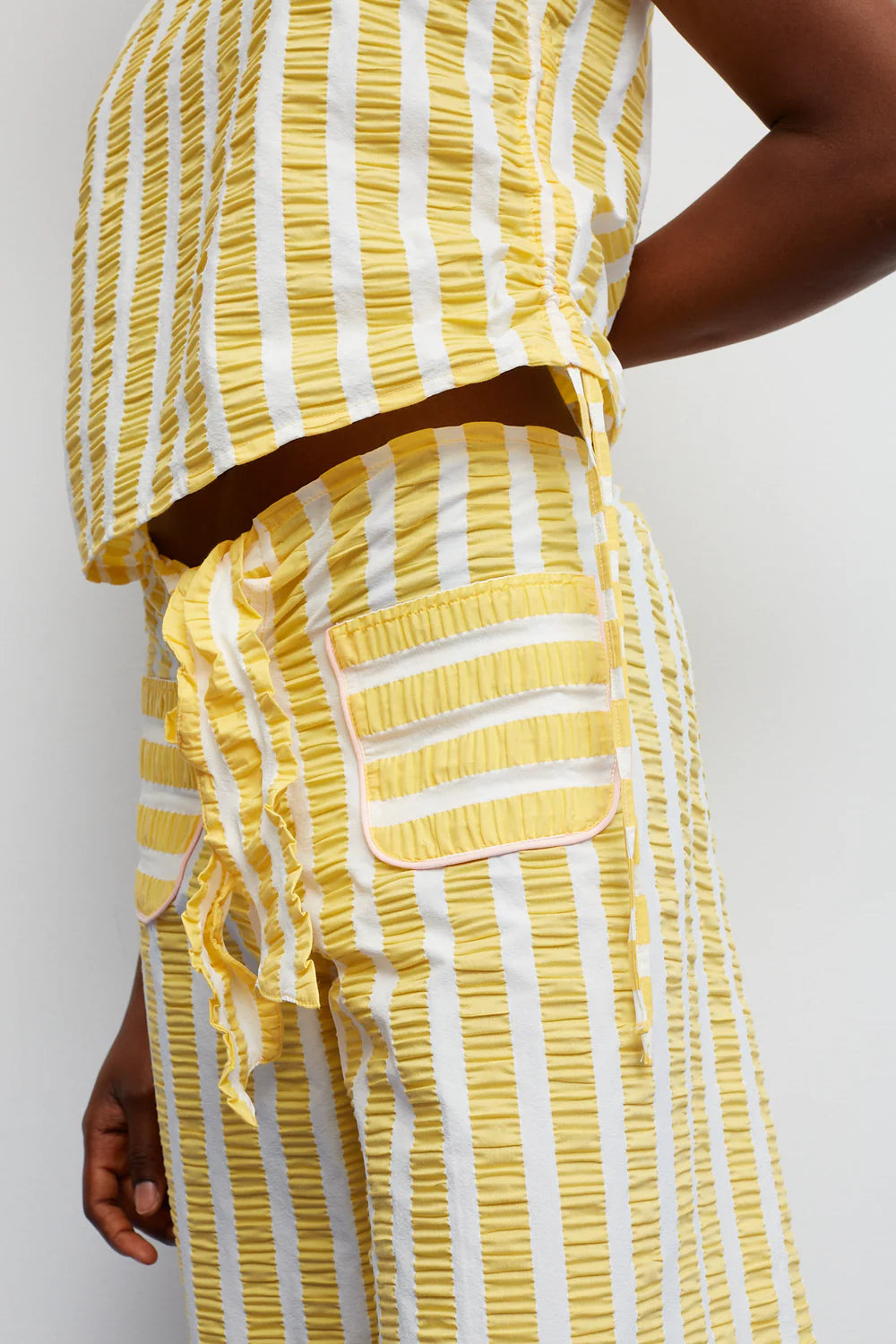 Yellow and white striped dress with a belt on a plain background