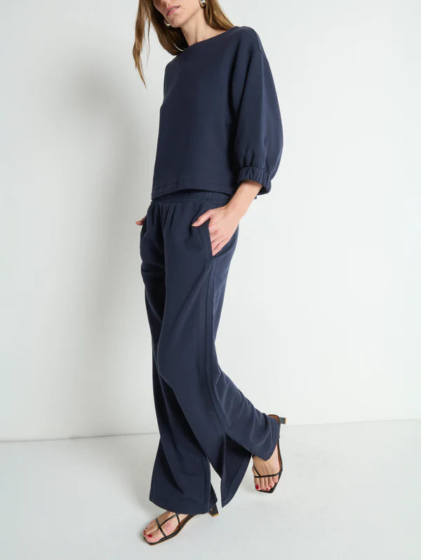 Person wearing a navy blue outfit with wide-leg pants and a matching top on a white background