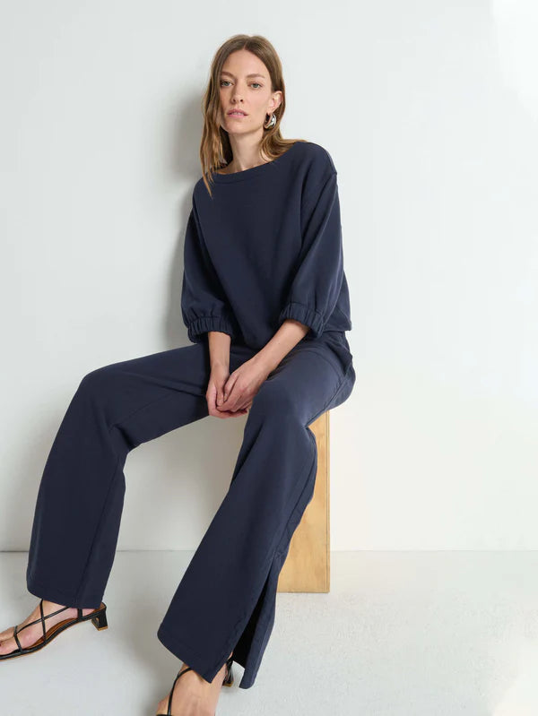 Woman wearing a navy blue outfit sitting on a white background
