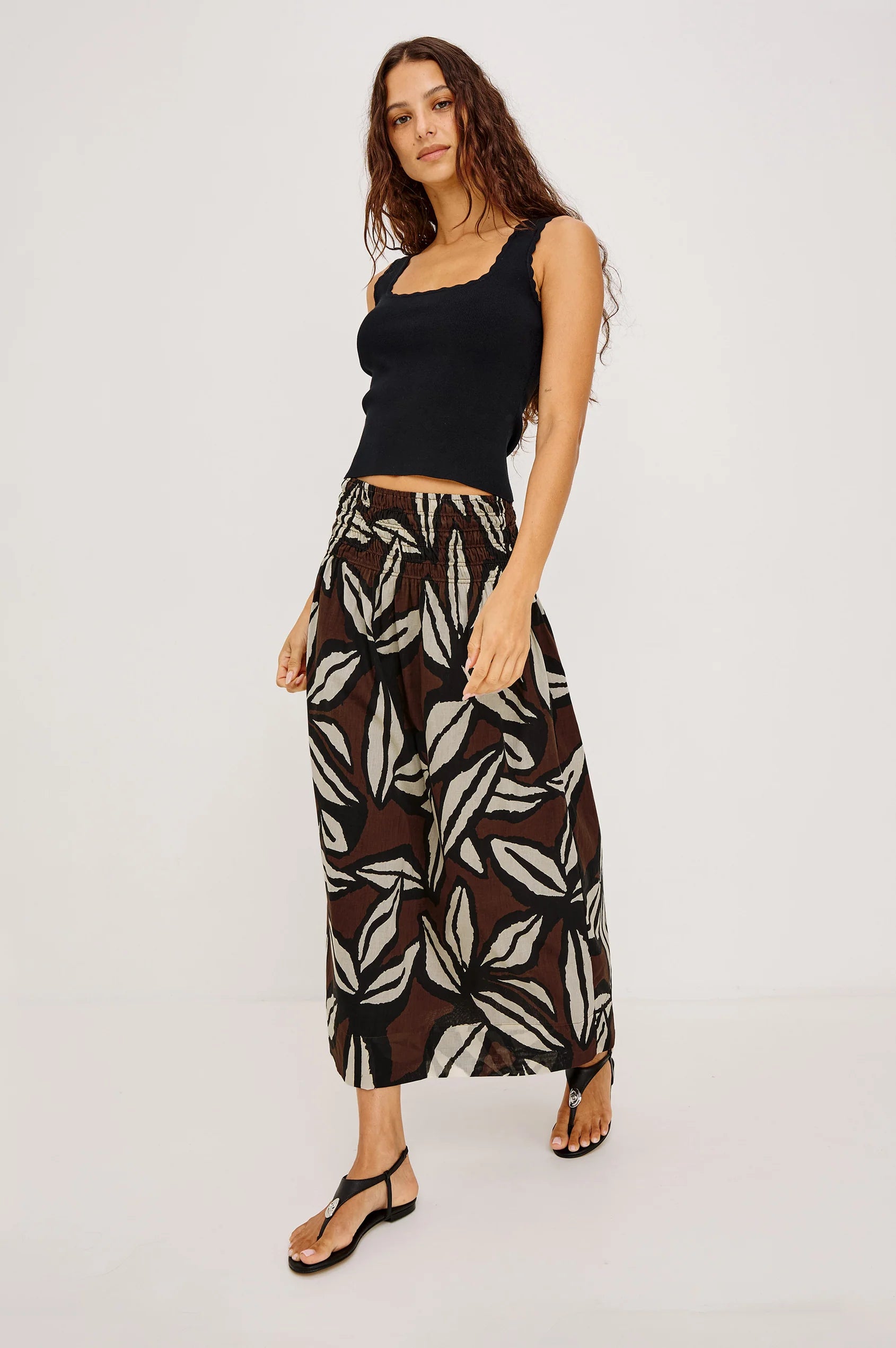 Woman wearing a black top and patterned pants on a white background