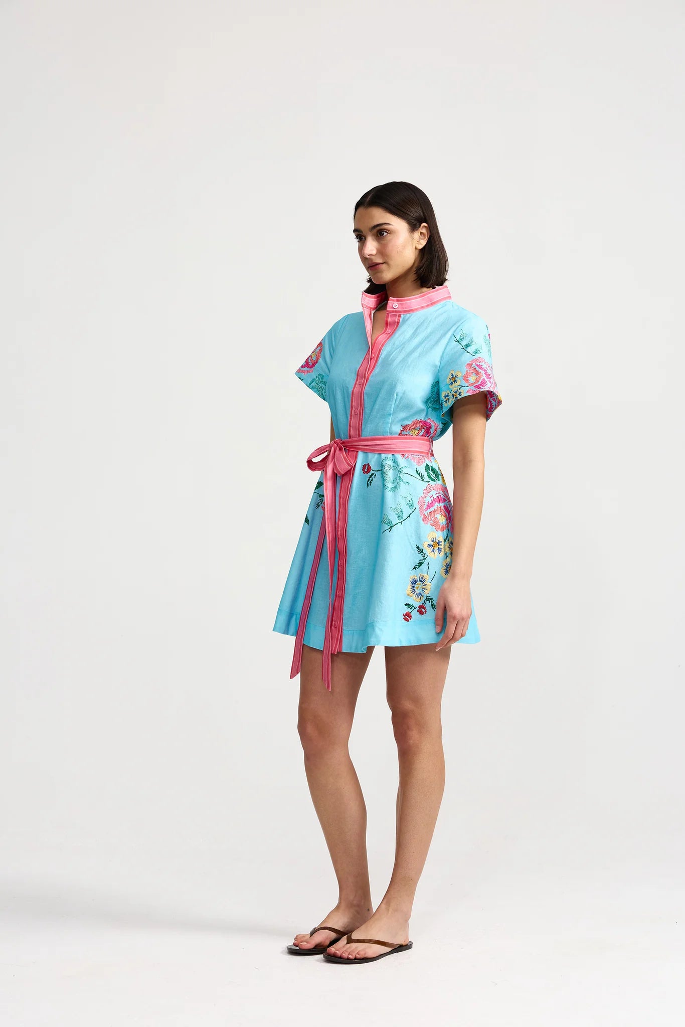 Woman wearing a light blue kimono-style dress with pink accents on a white background