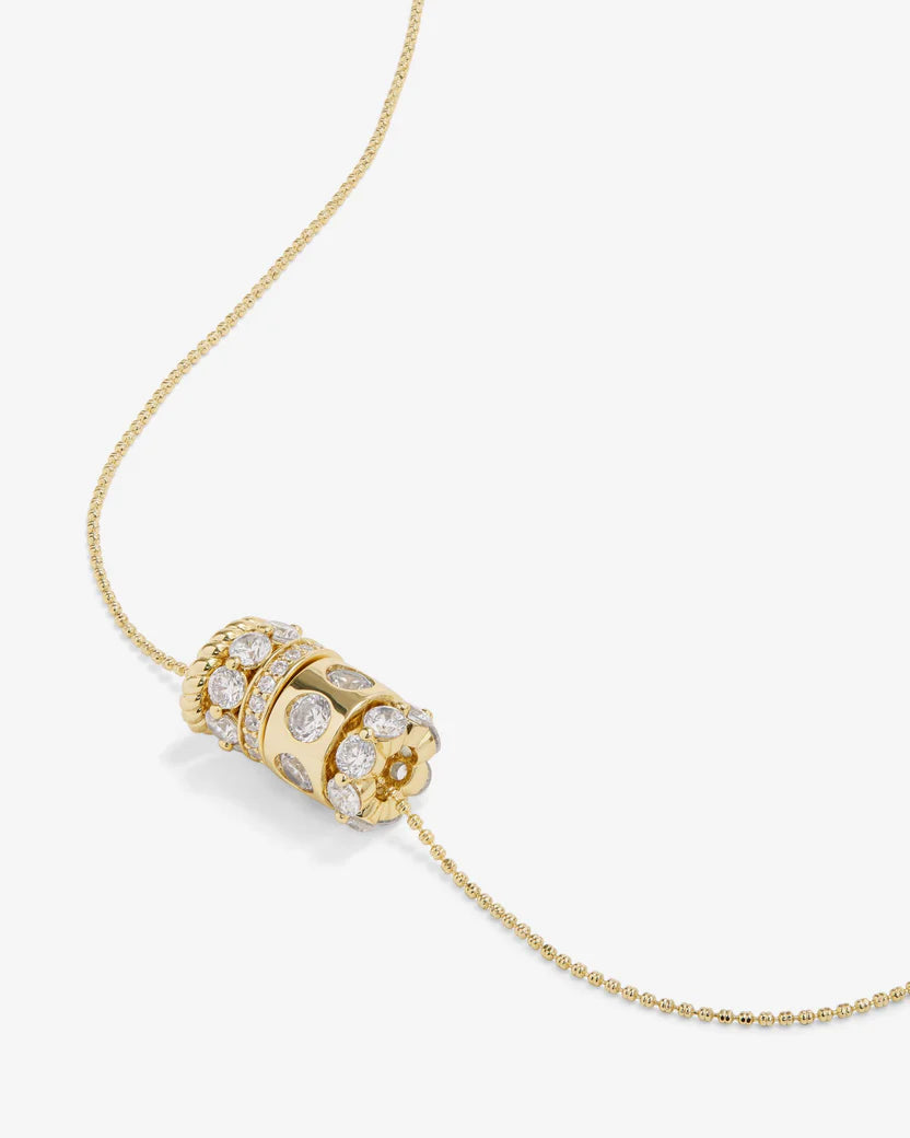Gold necklace with a cylindrical pendant on a white background