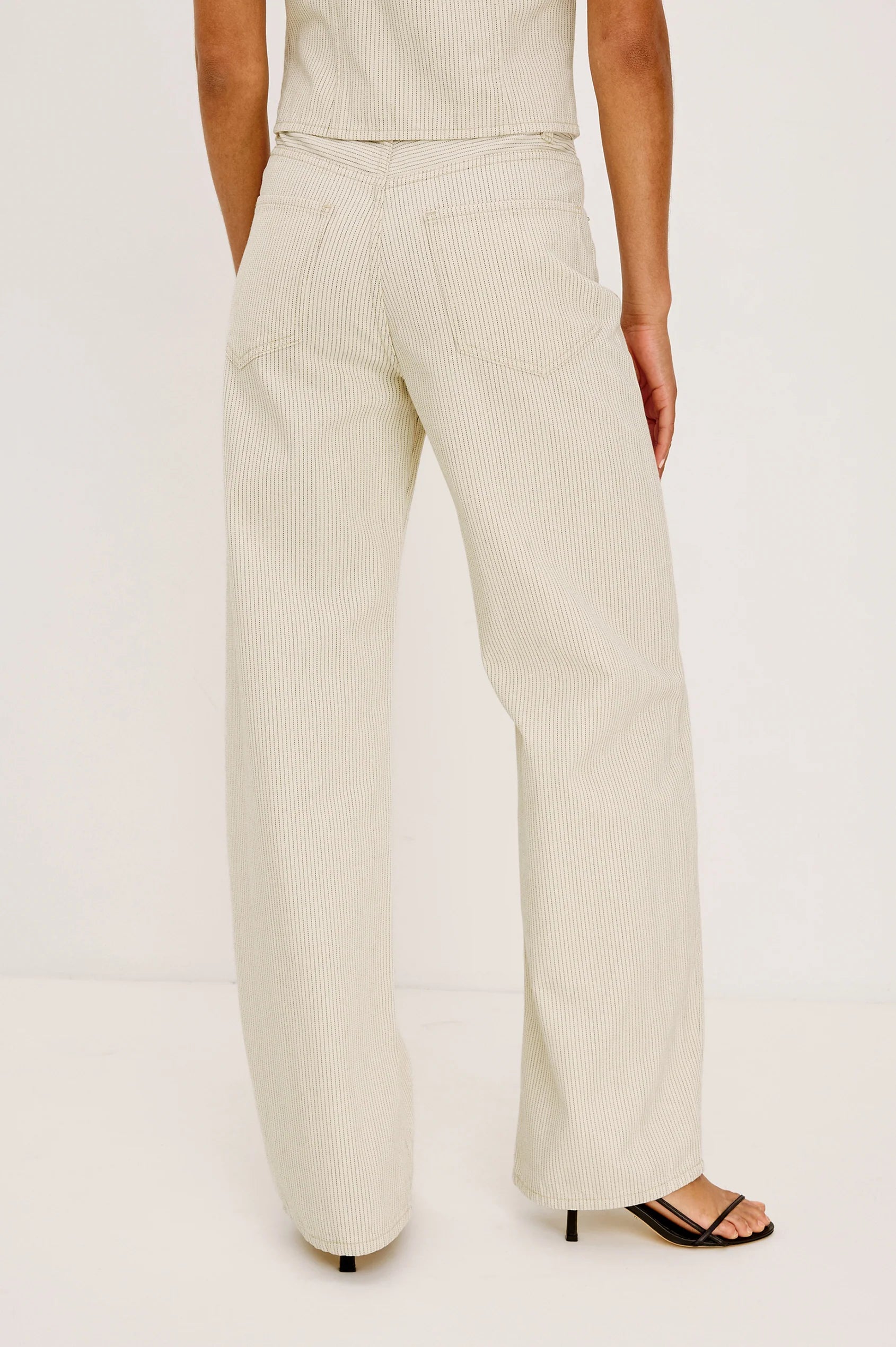 Person wearing a beige suit with wide-leg pants on a white background