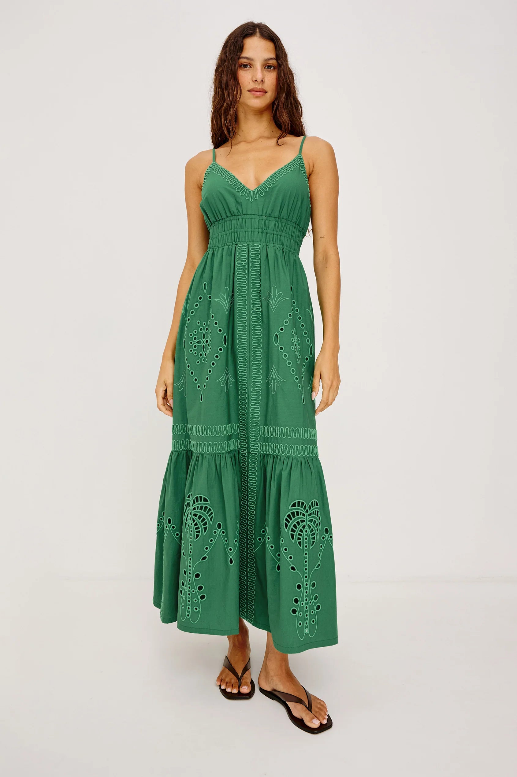 Woman wearing a green dress with cut-out patterns on a white background