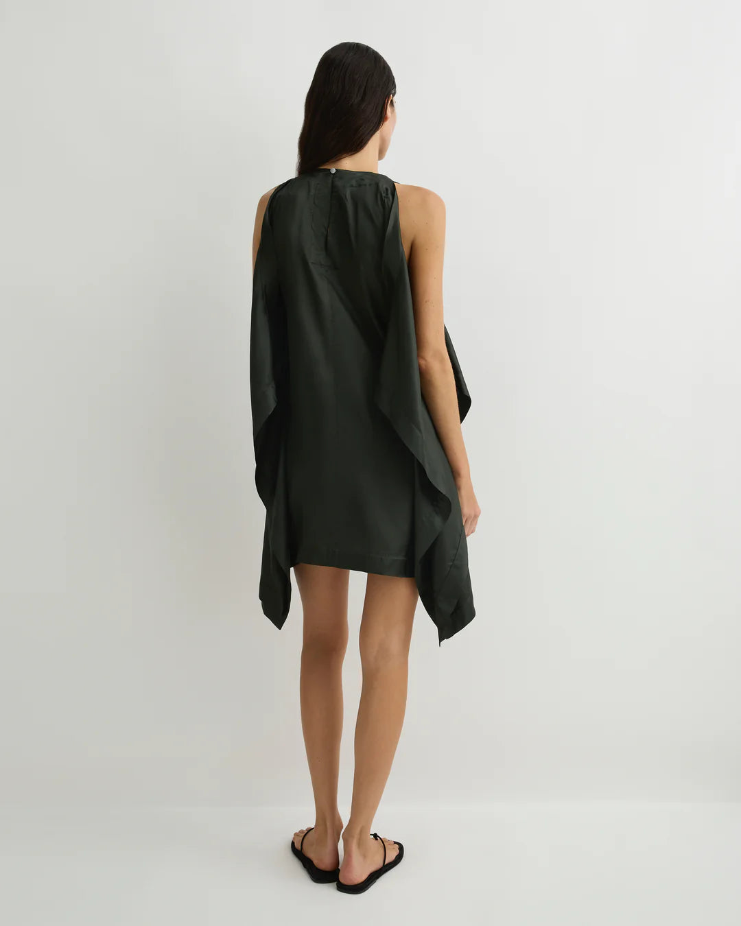 Woman wearing a dark green dress on a light gray background