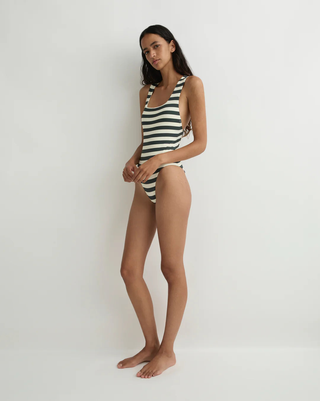 Woman wearing a black and white striped swimsuit on a plain background