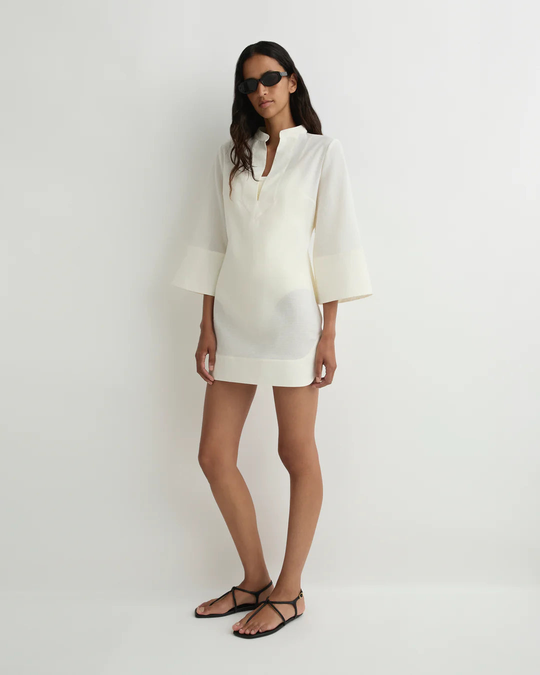 Woman wearing a white outfit with sunglasses on a plain background