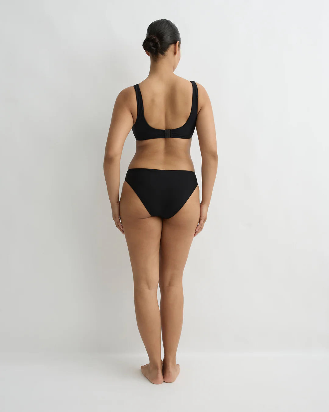 Person wearing a black bikini set on a plain background